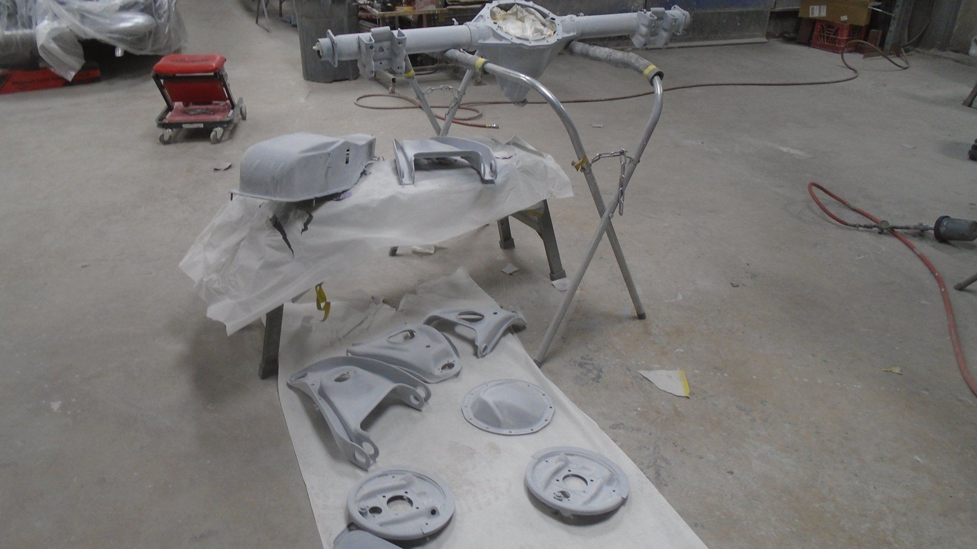 Car parts, sprayed with primer, on a table in a workshop.