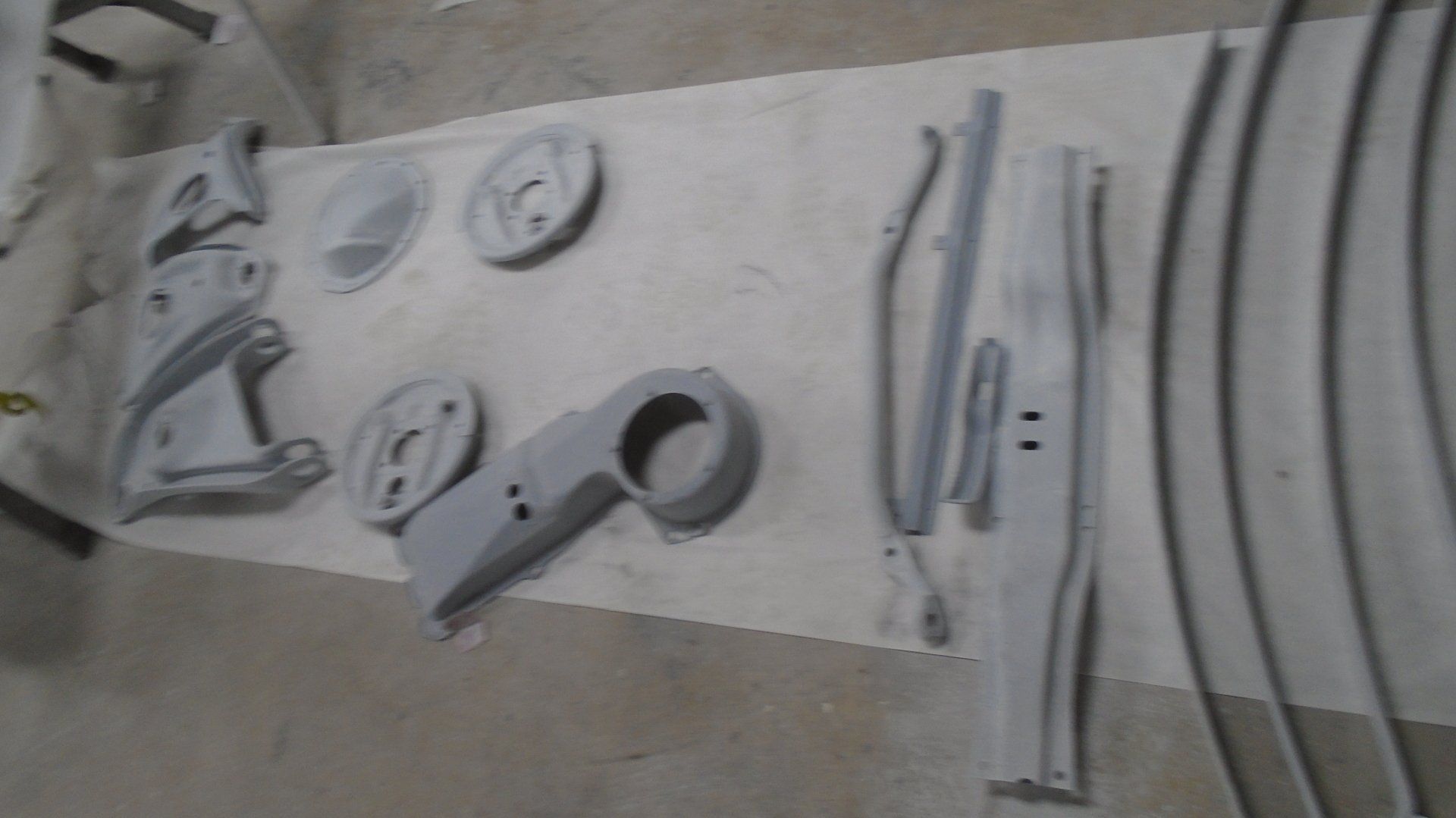 Gray automotive parts laid out for painting on a workbench.