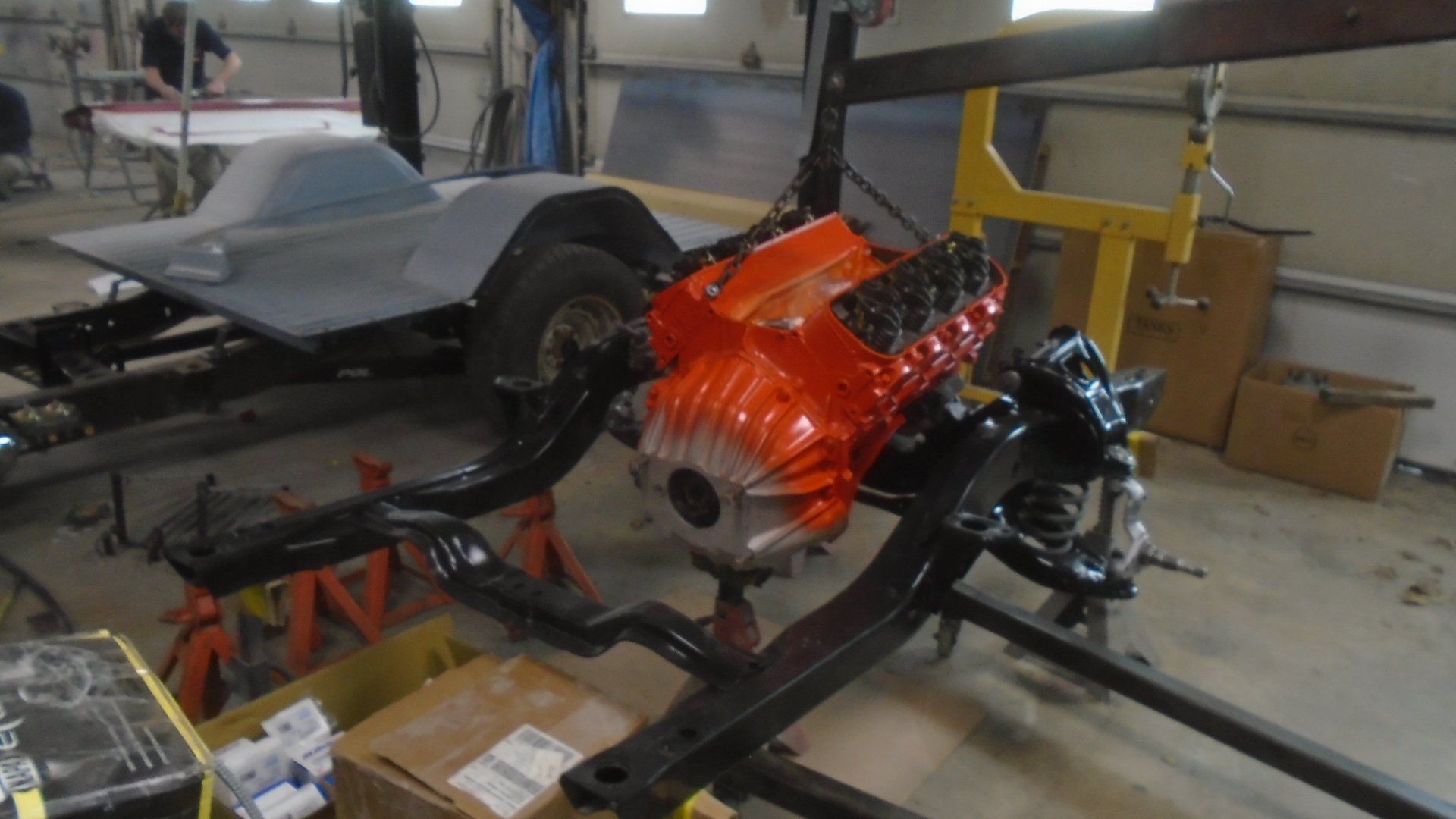 Assembled car chassis with orange engine, in a shop.