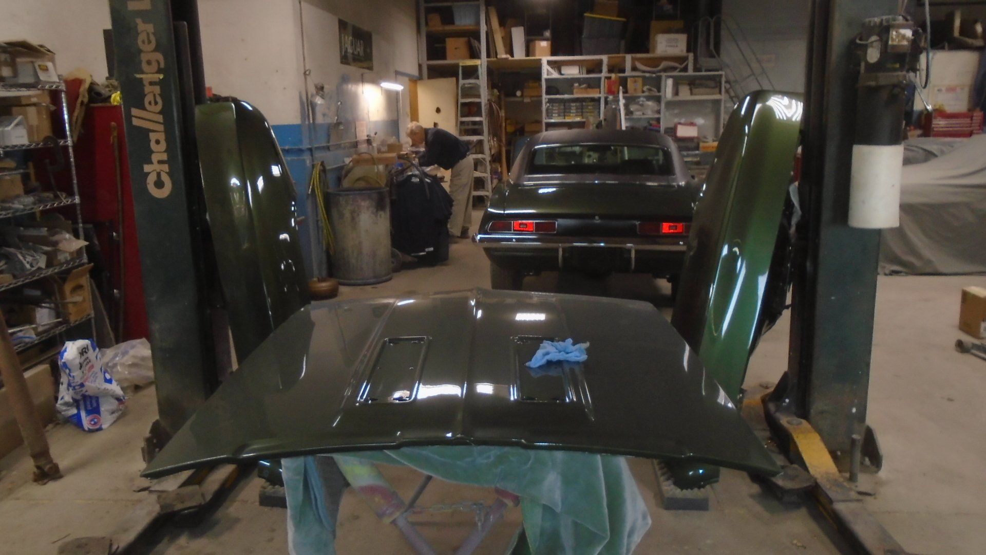 Green car parts displayed in a garage, a car is visible in the background.