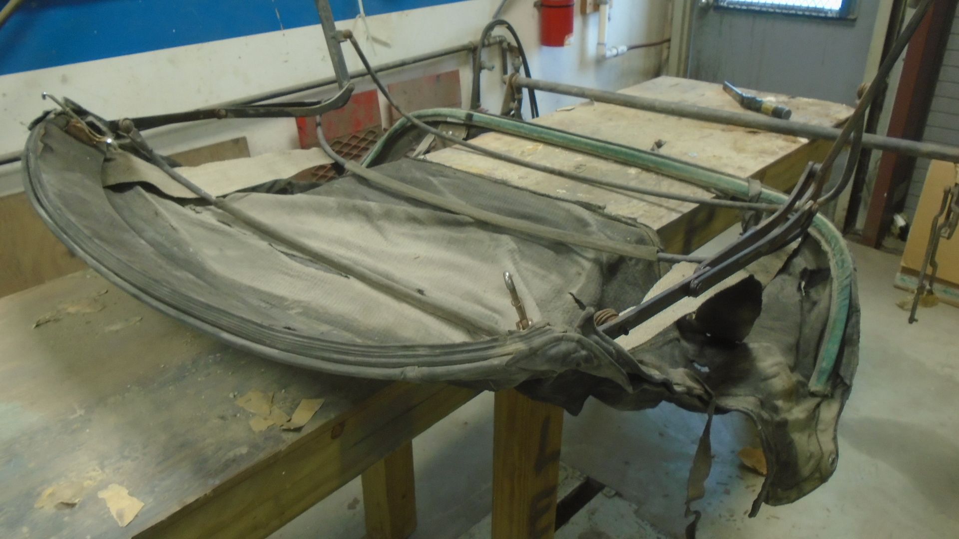Black convertible top frame on a workbench in a workshop. Fabric is attached.