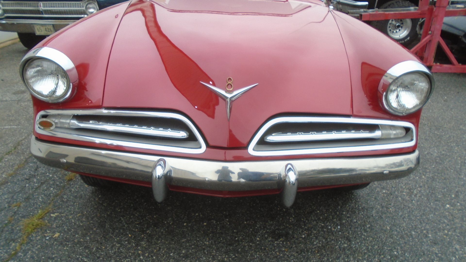 Red vintage Studebaker car front view with chrome accents and emblem.