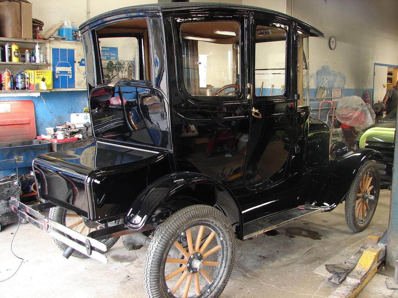 Black antique car with wooden wheels in a garage.