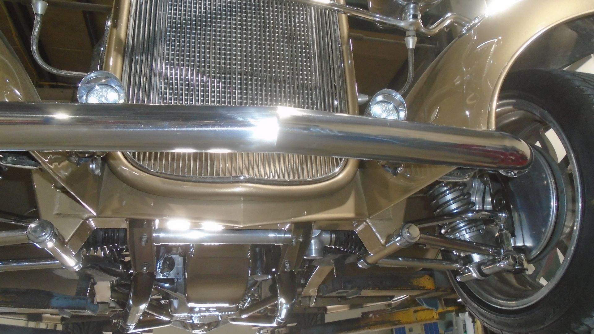 Undercarriage view of a classic gold hot rod, chrome details.
