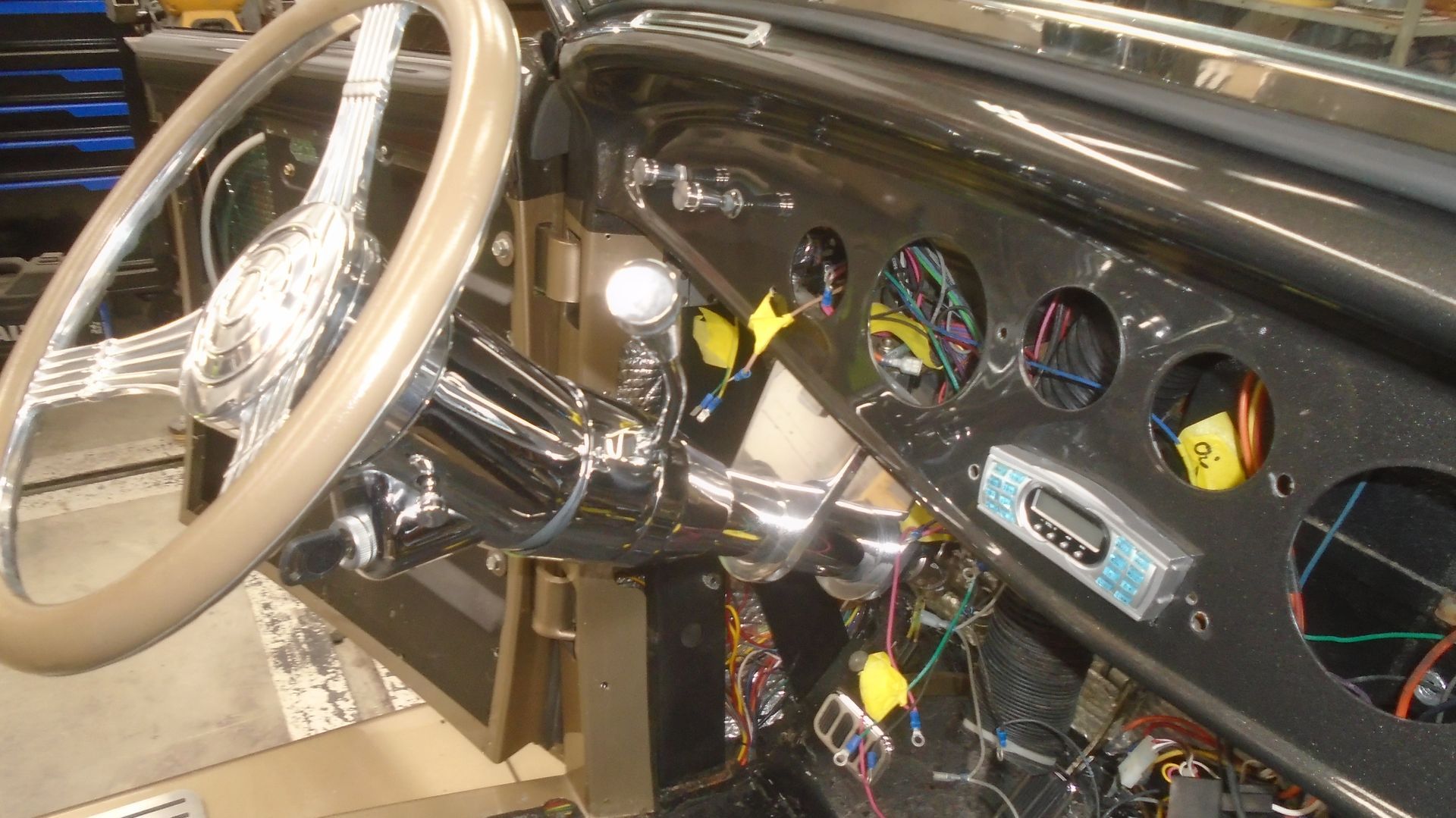 Dashboard interior of a vintage car with chrome steering wheel and gauges.