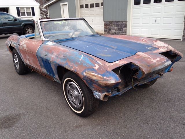 Blue and rust convertible car, front view, outdoors. White wall tires, missing parts, weathered paint.