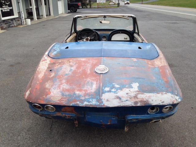 Rear view of a classic blue and red convertible car with weathered paint.