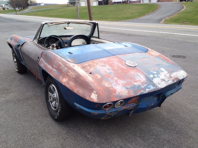 Vintage blue and rust colored convertible car, parked on a road.