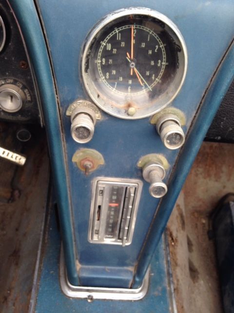 Blue dashboard of a classic car, featuring a clock, radio, and control knobs.
