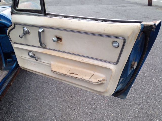 Blue car door with worn cream-colored interior panel and chrome handles.