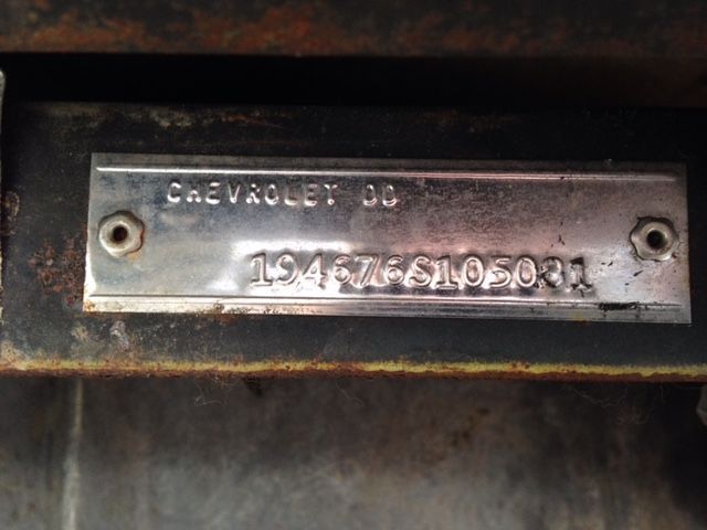 Silver Chevrolet data tag with stamped numbers and letters.