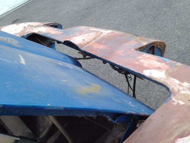 Blue car hood and rusted metal framework, possibly a classic car in process of restoration.