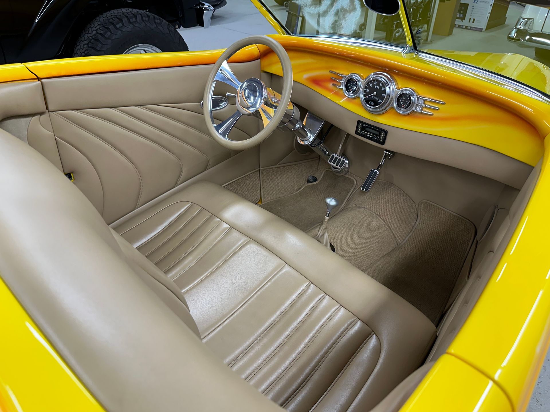 Yellow hot rod interior with tan seats, steering wheel, and dashboard.