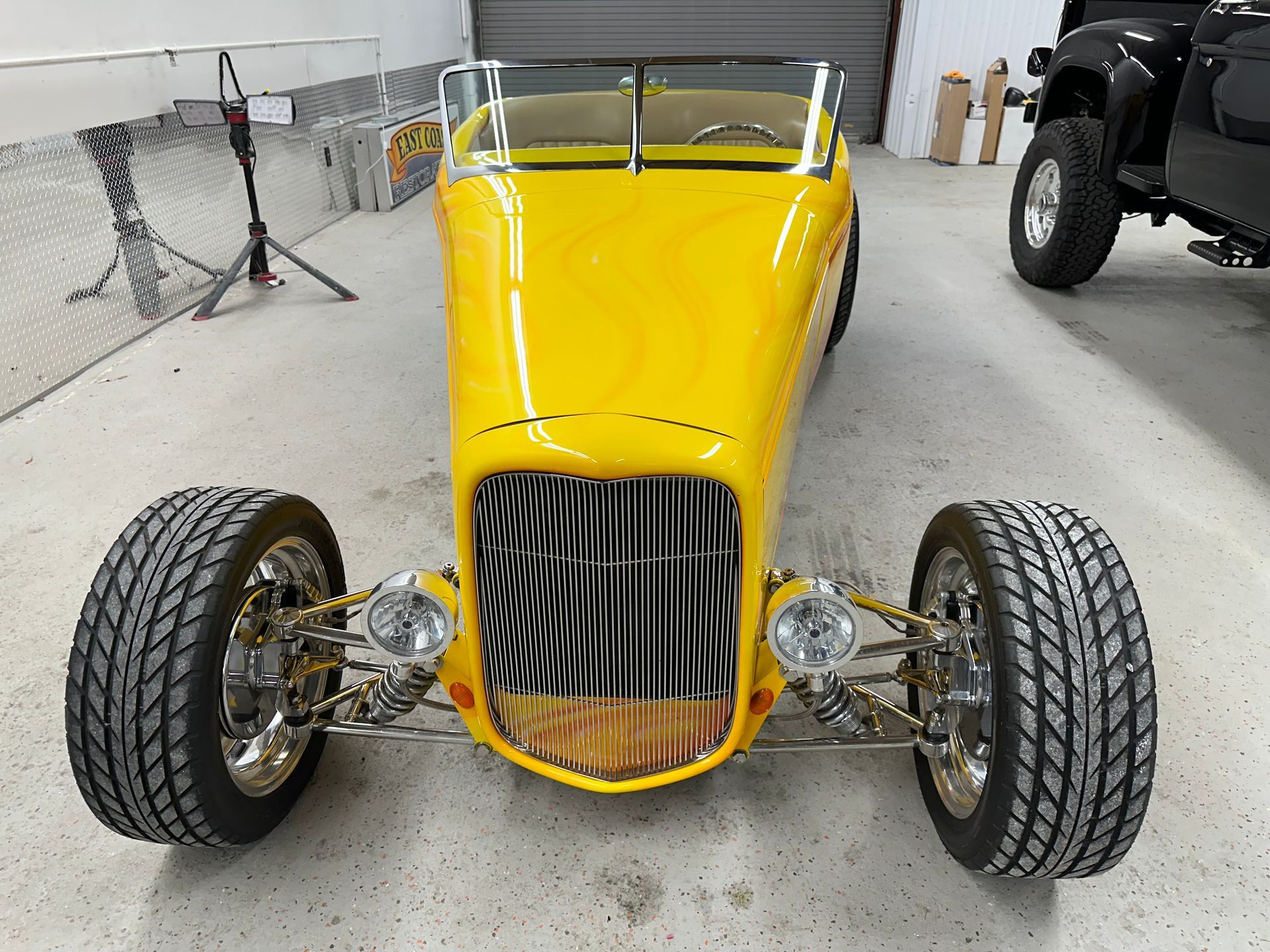 Yellow hot rod with chrome accents and large tires, parked in a garage.