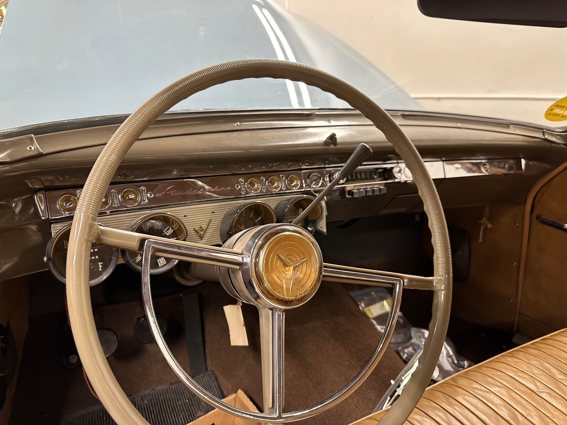 Interior of a vintage car: steering wheel, dashboard with gauges, gold emblem on the steering wheel