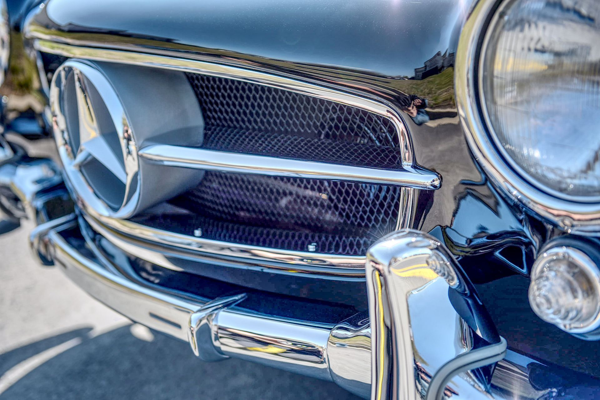 Close-up of a classic black Mercedes-Benz front end. Chrome grill and emblem detail, with headlight visible.