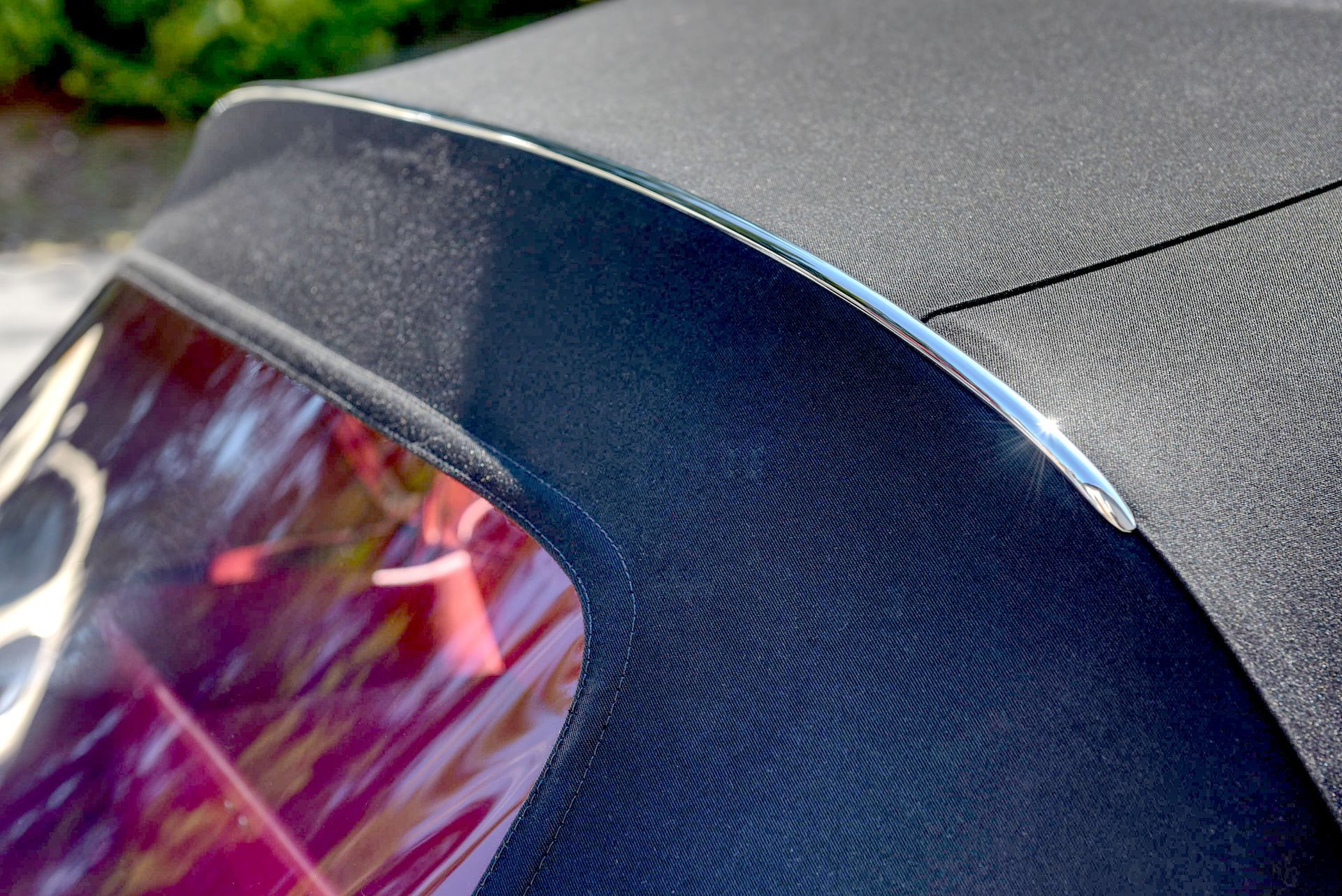 Black convertible car top with silver trim and rear window.