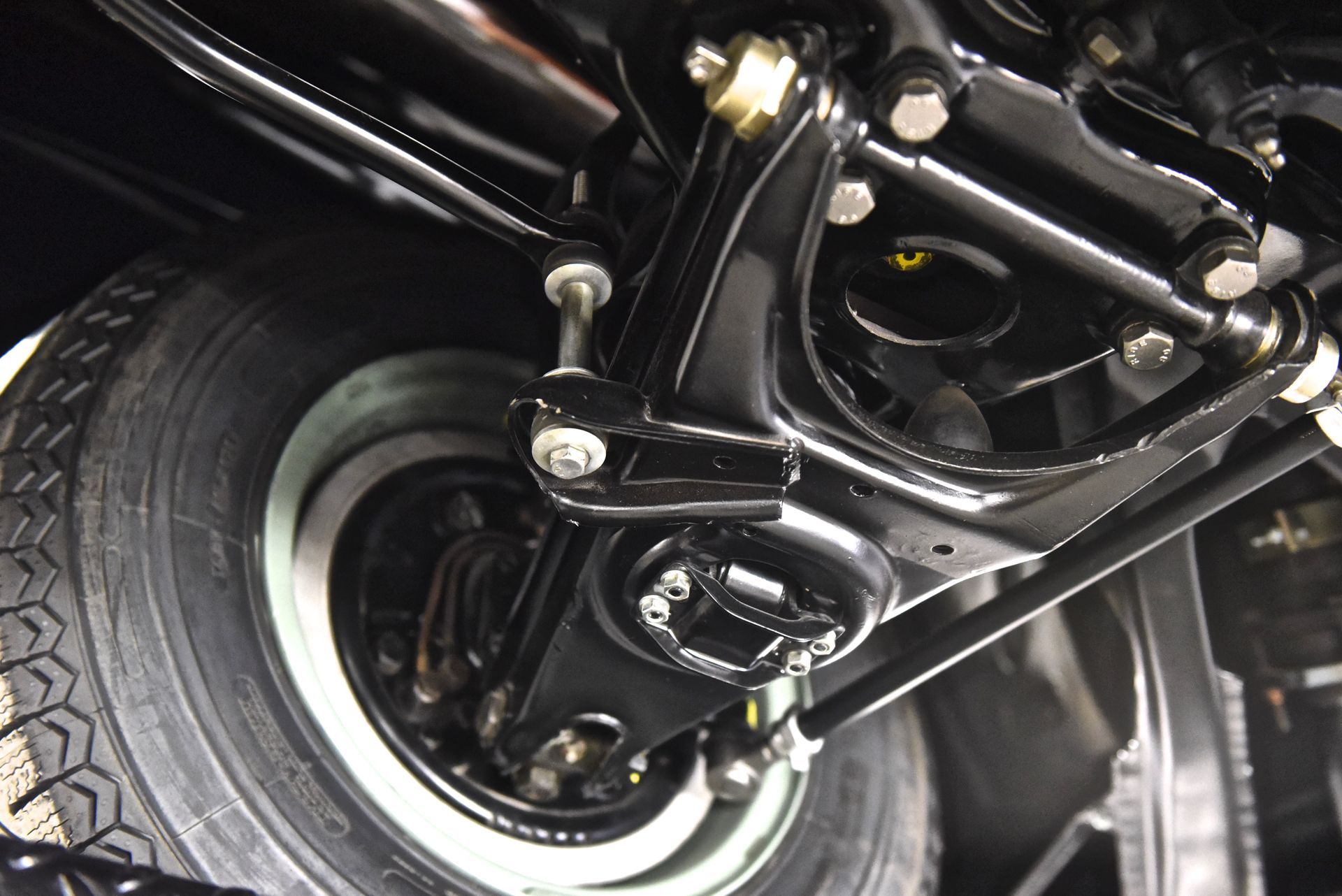 Black car suspension system with tire, undercarriage detail.