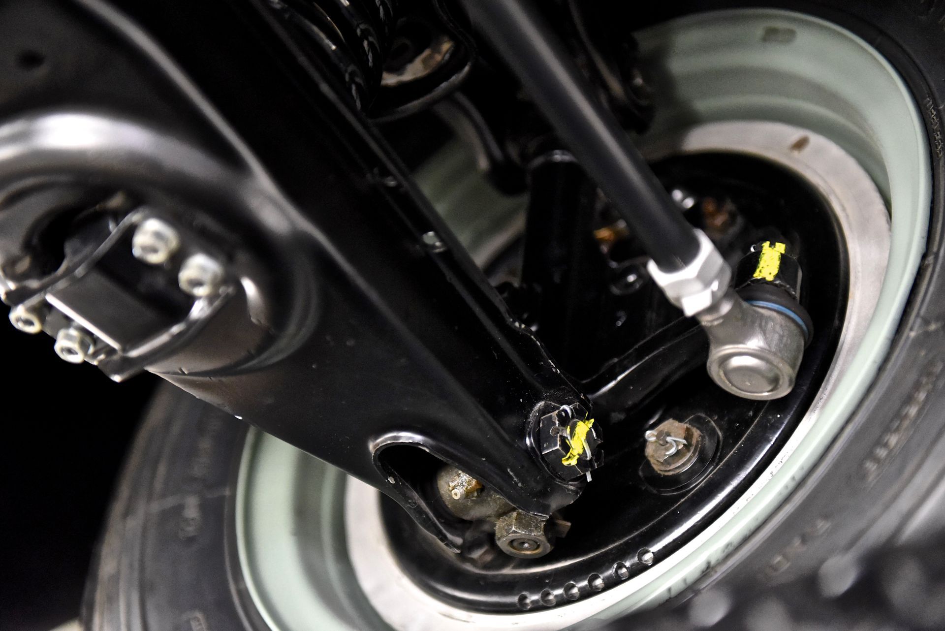 Black vehicle suspension with a white tire and silver hardware.