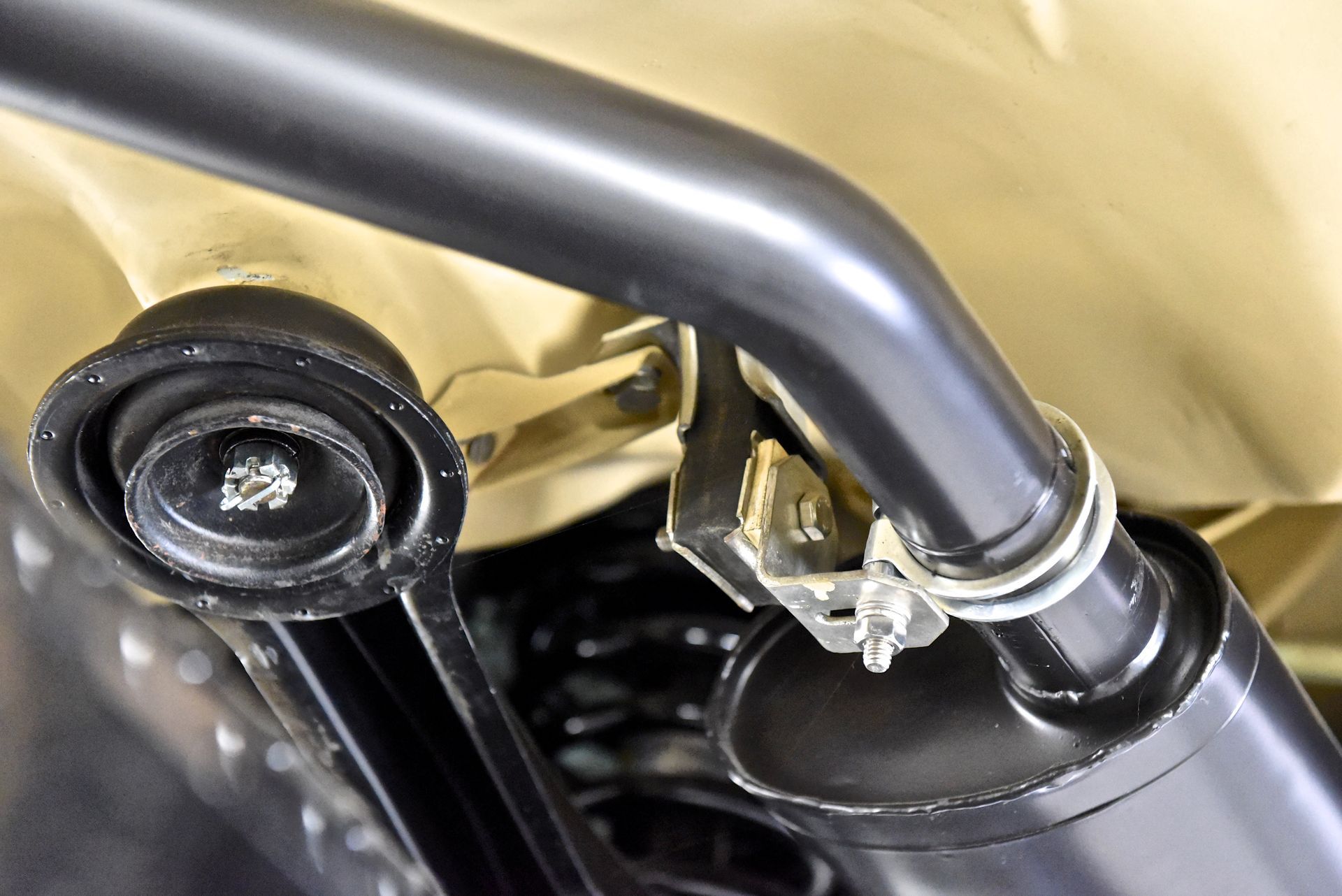 Black metal car suspension bar with a rubber bushing and bracket.