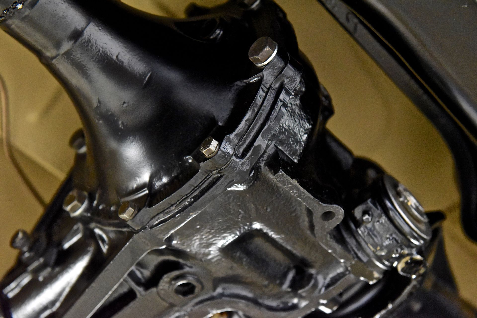 Black painted car differential housing with several bolts.