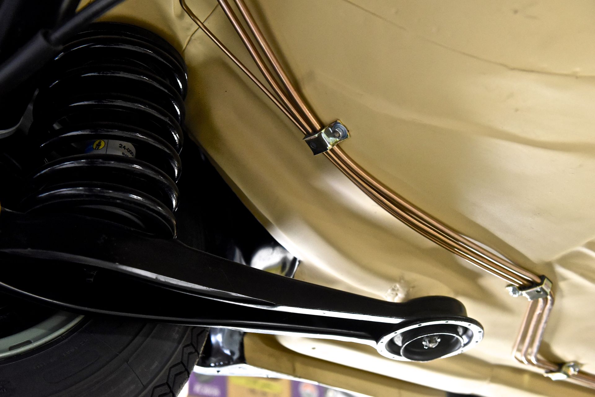 Undercarriage of a classic vehicle, showing suspension, brake lines, and chassis components.