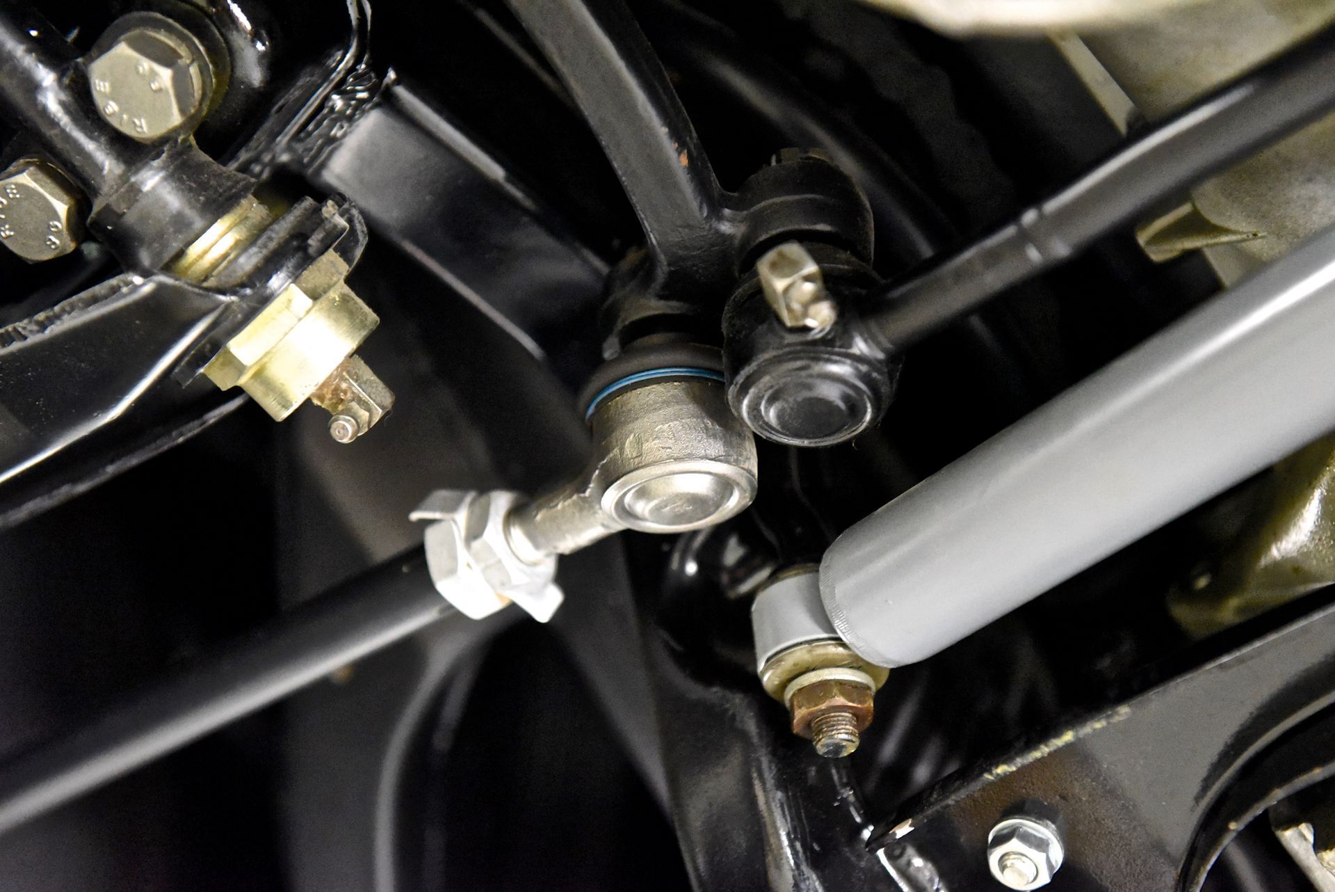 Black car suspension components: tie rods, ball joints, and a gray stabilizer bar.