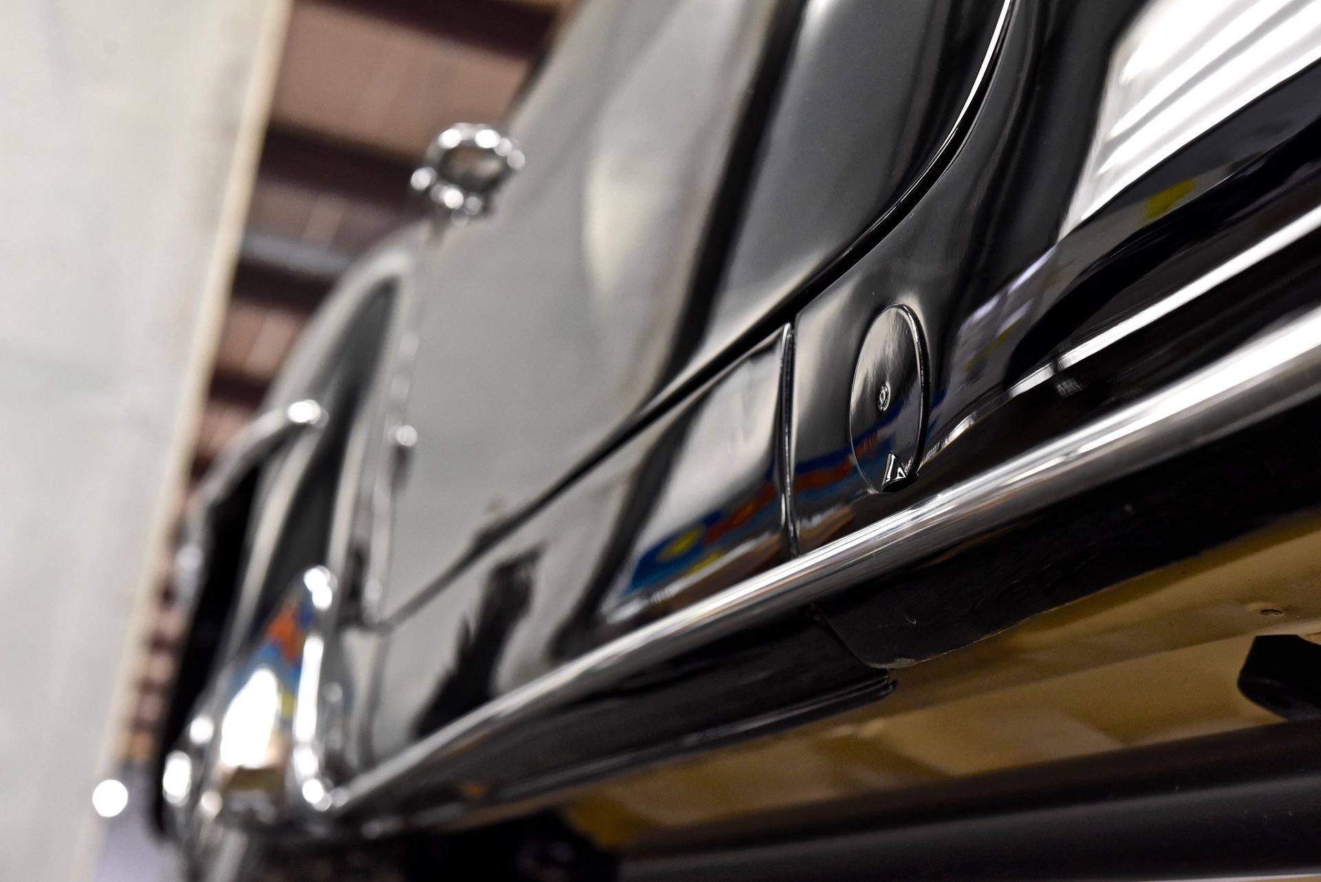 Black car side with chrome trim and reflections, viewed from below.
