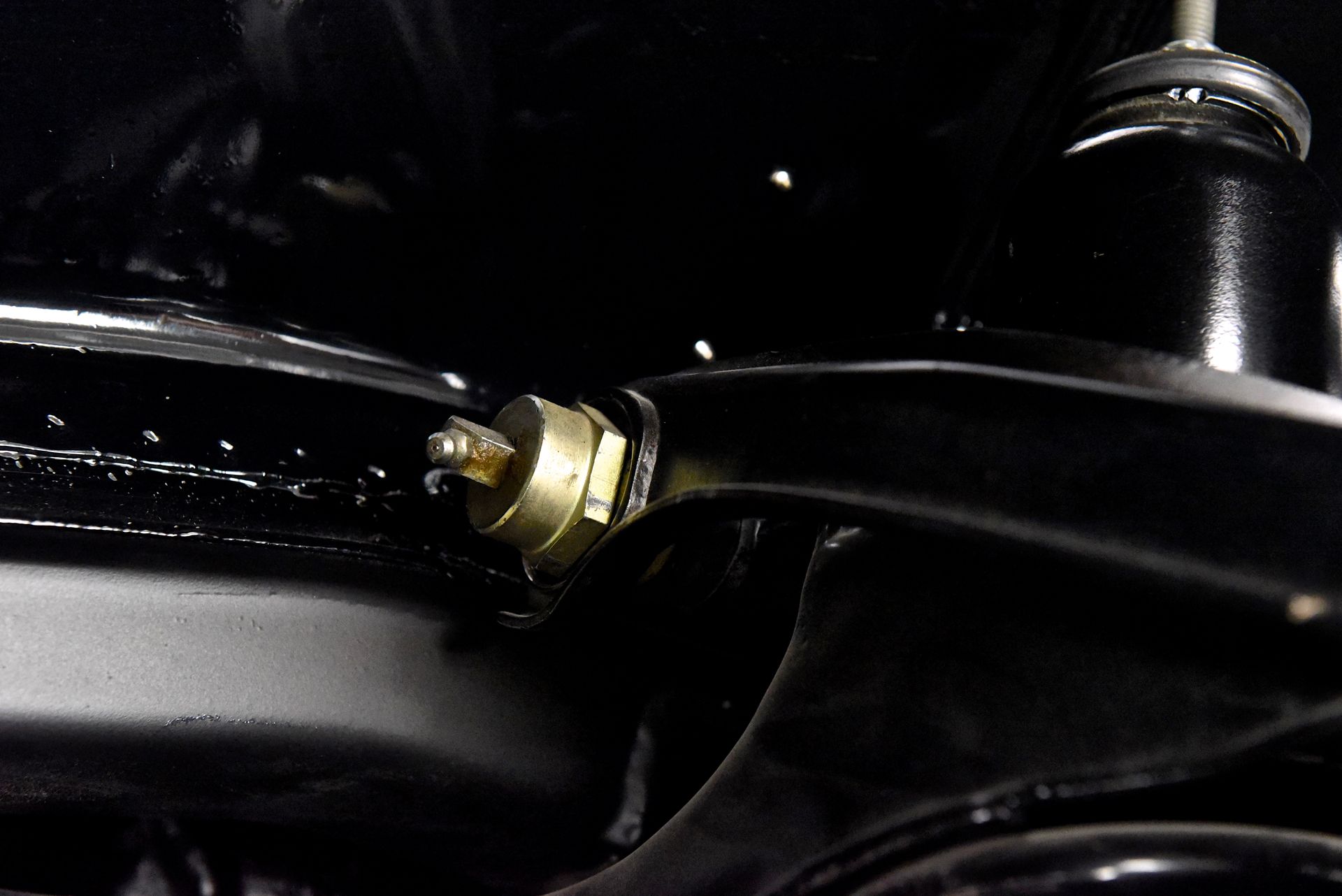 Brass fitting in black vehicle suspension.