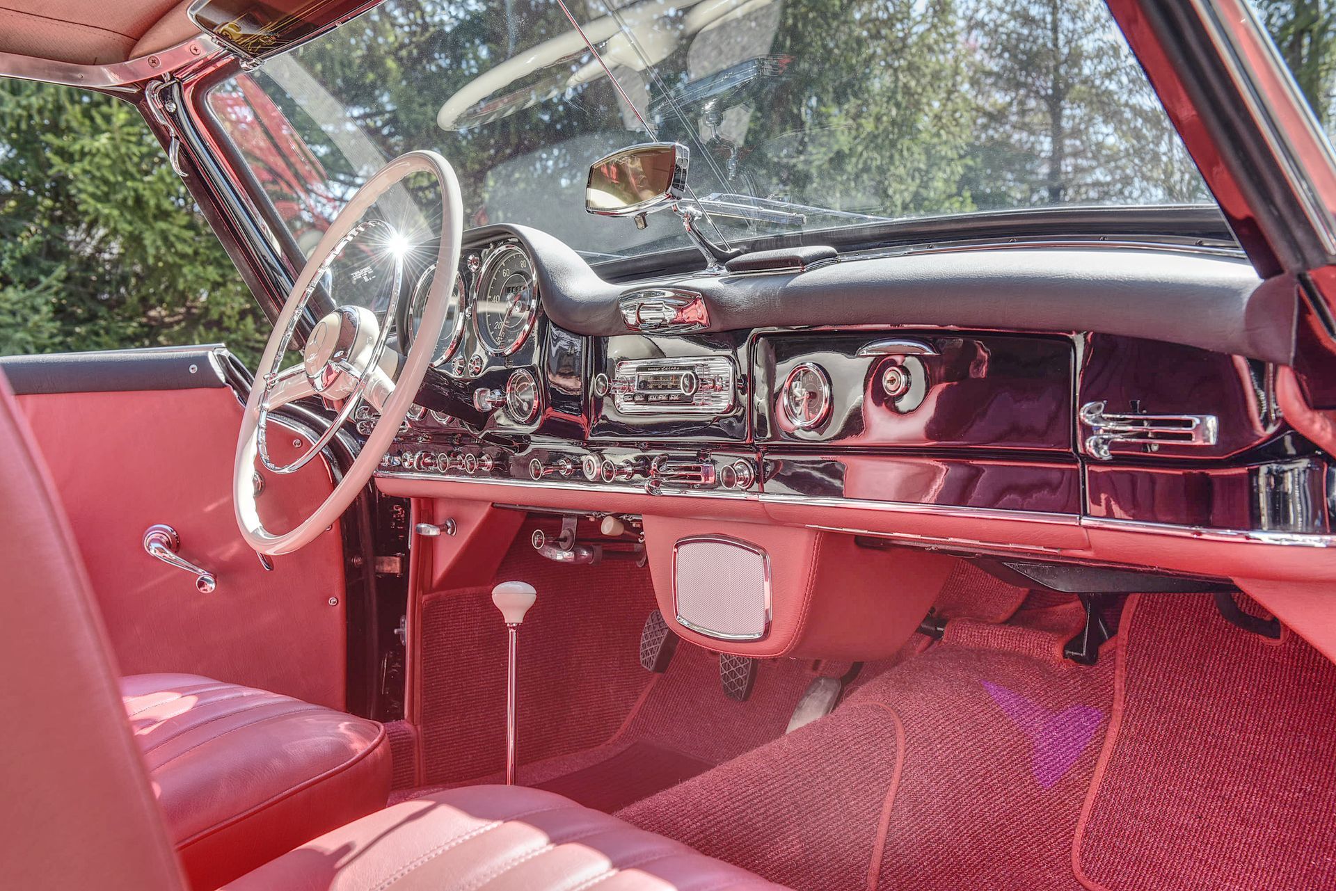 Interior of a classic pink convertible car, showing steering wheel, dashboard, and seats.