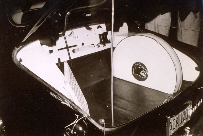 Trunk of a classic car with a large, spare tire visible.