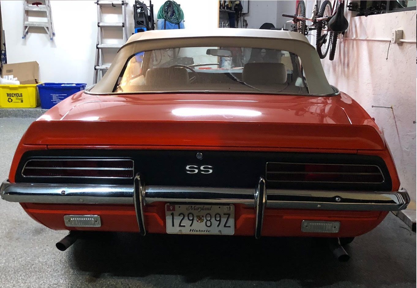 Rear view of a red and black classic convertible car with a white top in a garage. 
