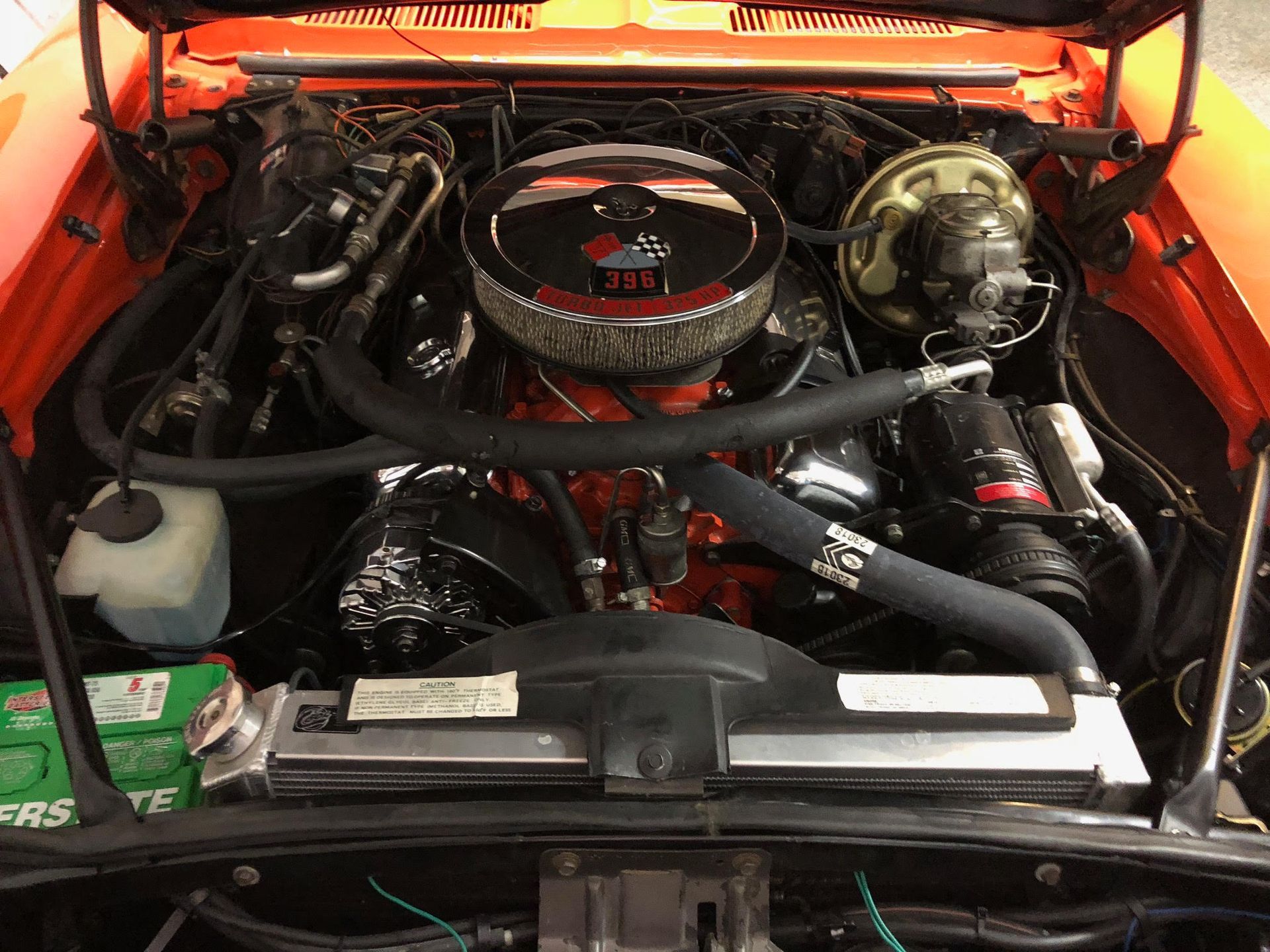 Orange engine bay of a classic car, with a large air cleaner and various components.