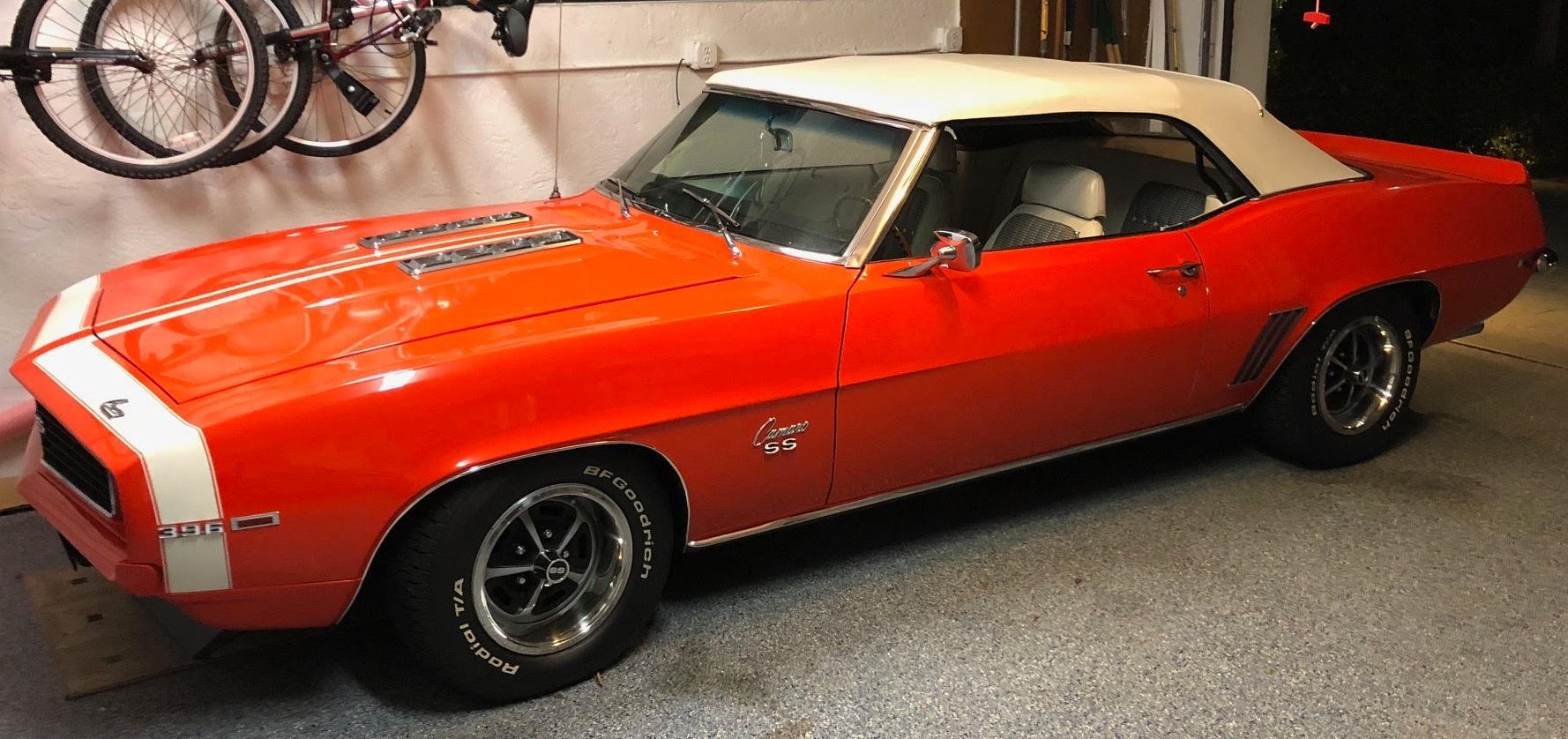 Red and white classic convertible car with white top in a garage.