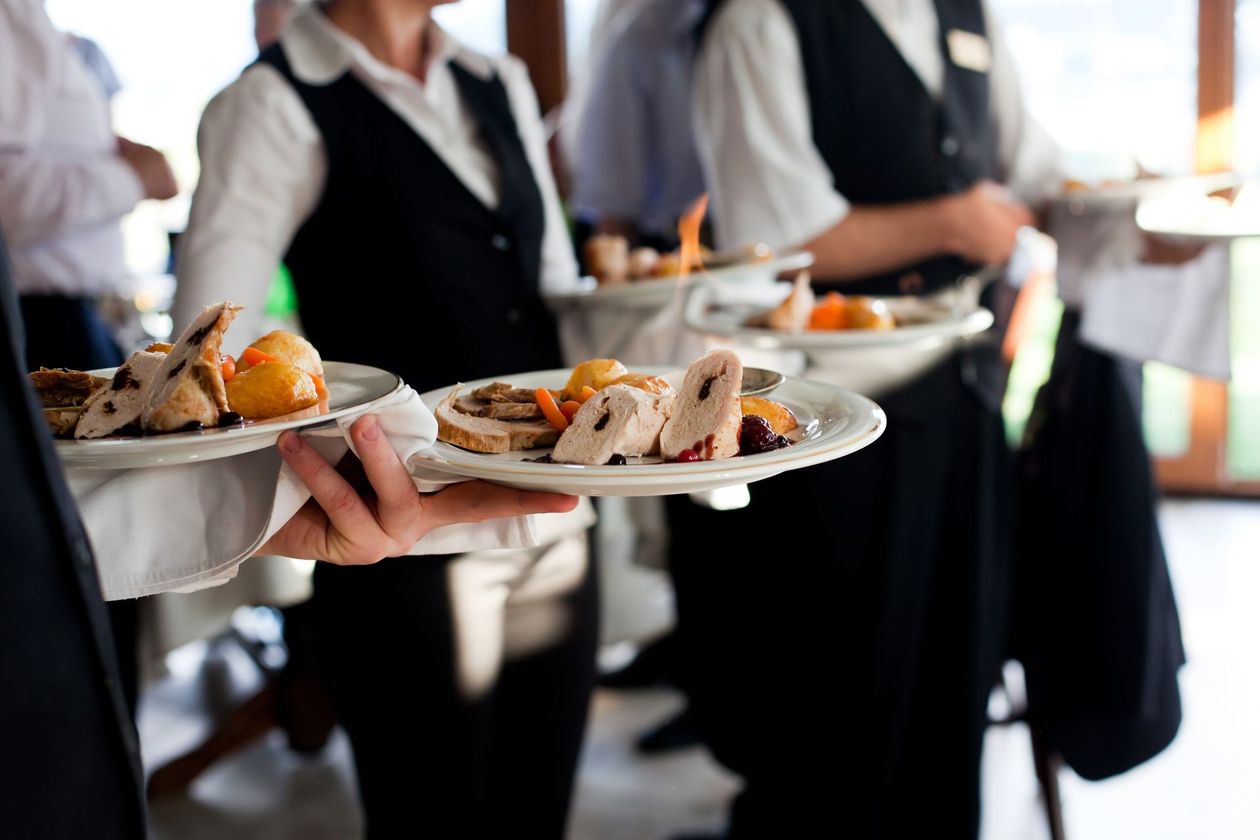 a group of waiters are holding plates of food in their hands