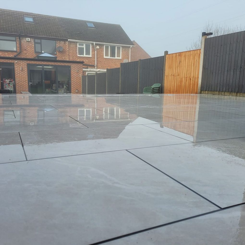 Wide grey porcelain patio behind a semi-detached house with new fencing
