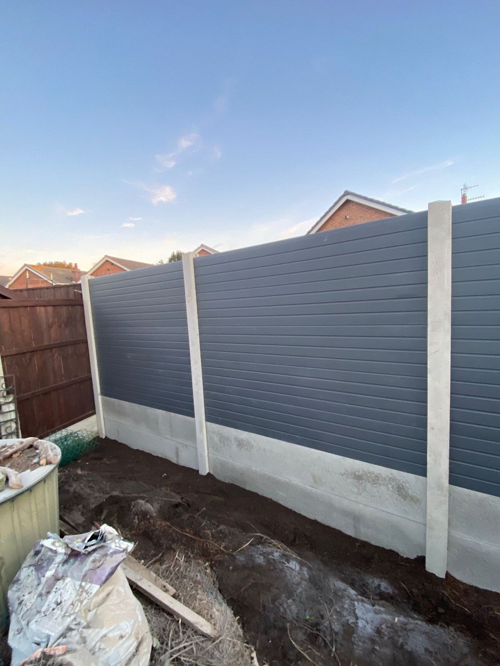 Grey composite fence panels fitted between concrete posts with concrete gravel boards