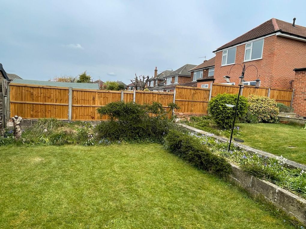 Replacement closeboard timber fencing along the back of a garden with a lawn and planted border
