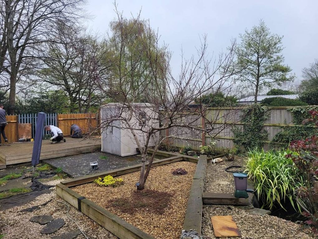 The Wyken garden before work began, with old decking, a pond, gravel and timber edging