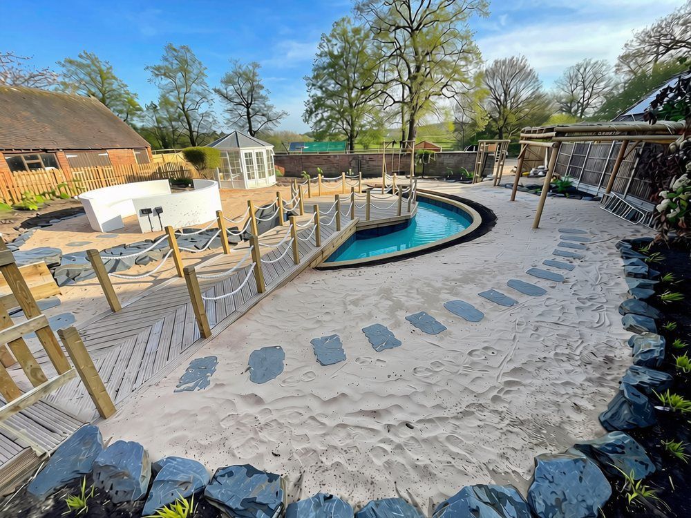Beach-style sand garden with slate stepping stones, slate-edged planting, a herringbone jetty with rope balustrade and a curved lagoon