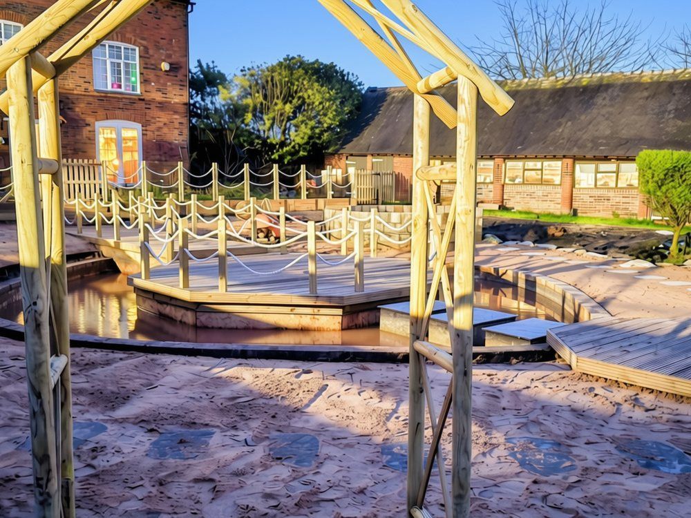 Timber swing frame on beach-style sand with stepping stones leading towards the lagoon, rope-edged island deck and a small octagonal deck