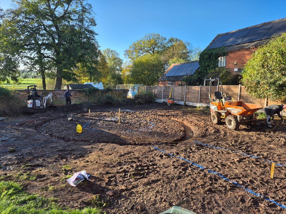 Mini digger and dumper excavating a large garden with the curved lagoon shape marked out in blue paint at Top Leather Mill Farm, Atherstone