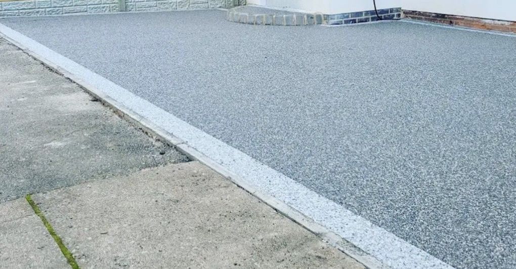 Grey resin bound driveway with a pale border meeting the pavement