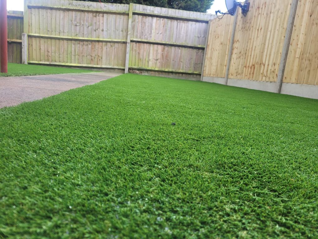 Low view across a new artificial lawn beside a path and new fencing