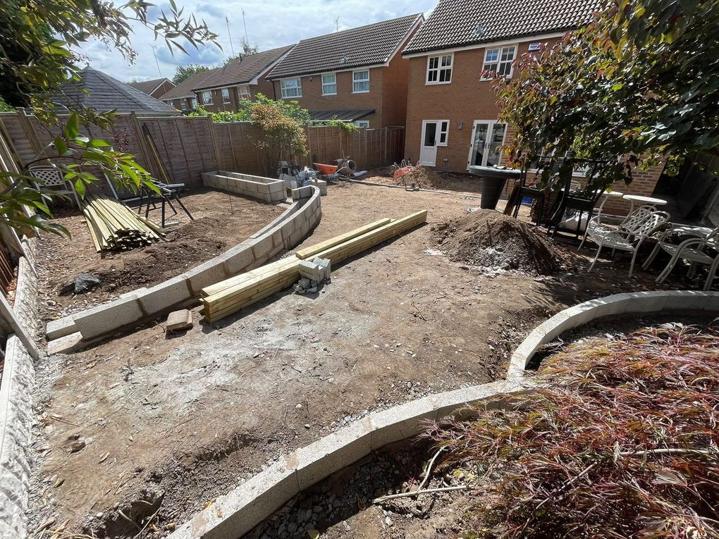 Curved blockwork walls being built across a cleared garden in Balsall Common