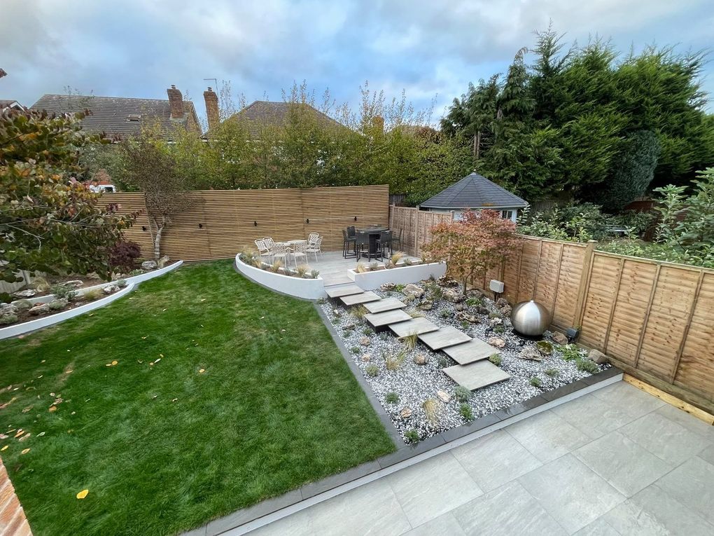 Overview of the finished garden with lawn, curved rendered walls, floating steps and a raised seating area