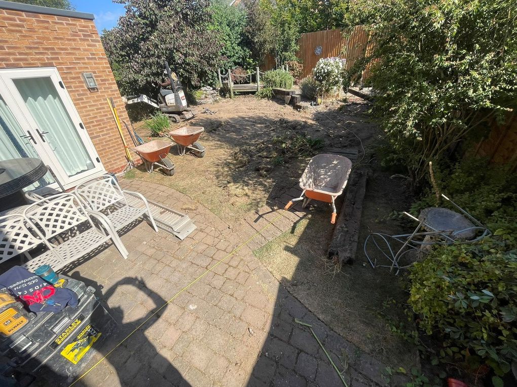 The Tid Marsh Close garden before work began, with old block paving, overgrown borders and wheelbarrows on site