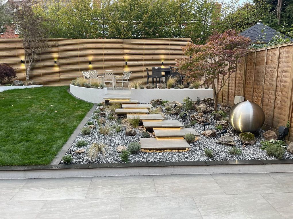 Finished garden in Balsall Common with floating porcelain steps, a stainless steel sphere water feature, curved rendered walls and Venetian screening