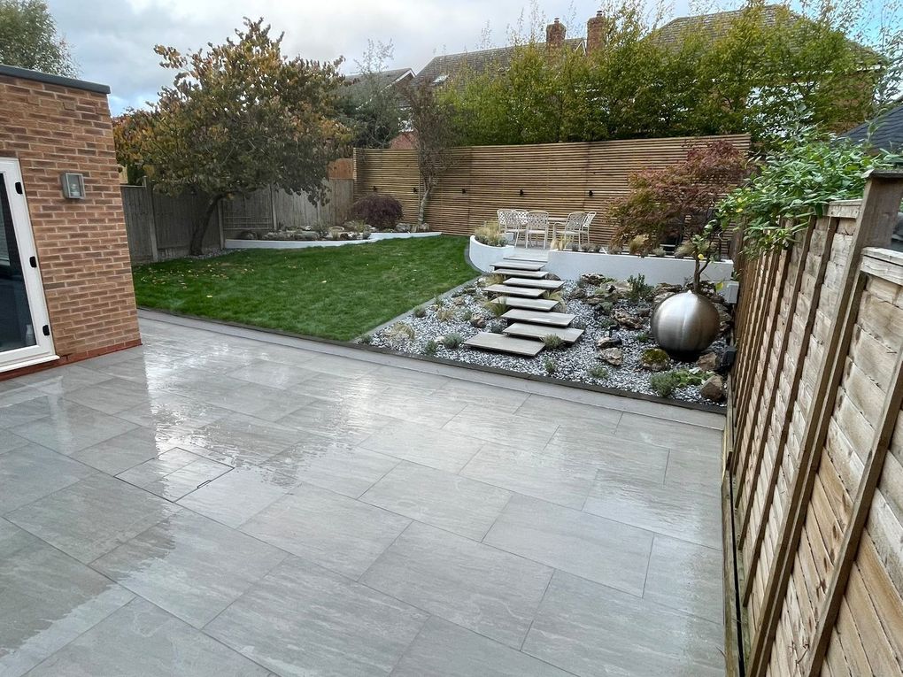 Lower porcelain patio looking across the lawn to the floating steps, raised seating area and screening