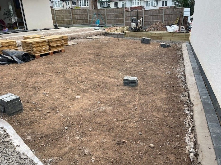 Coundon garden during the build, levelled bare earth with timber sleepers and porcelain paving stacked ready to lay